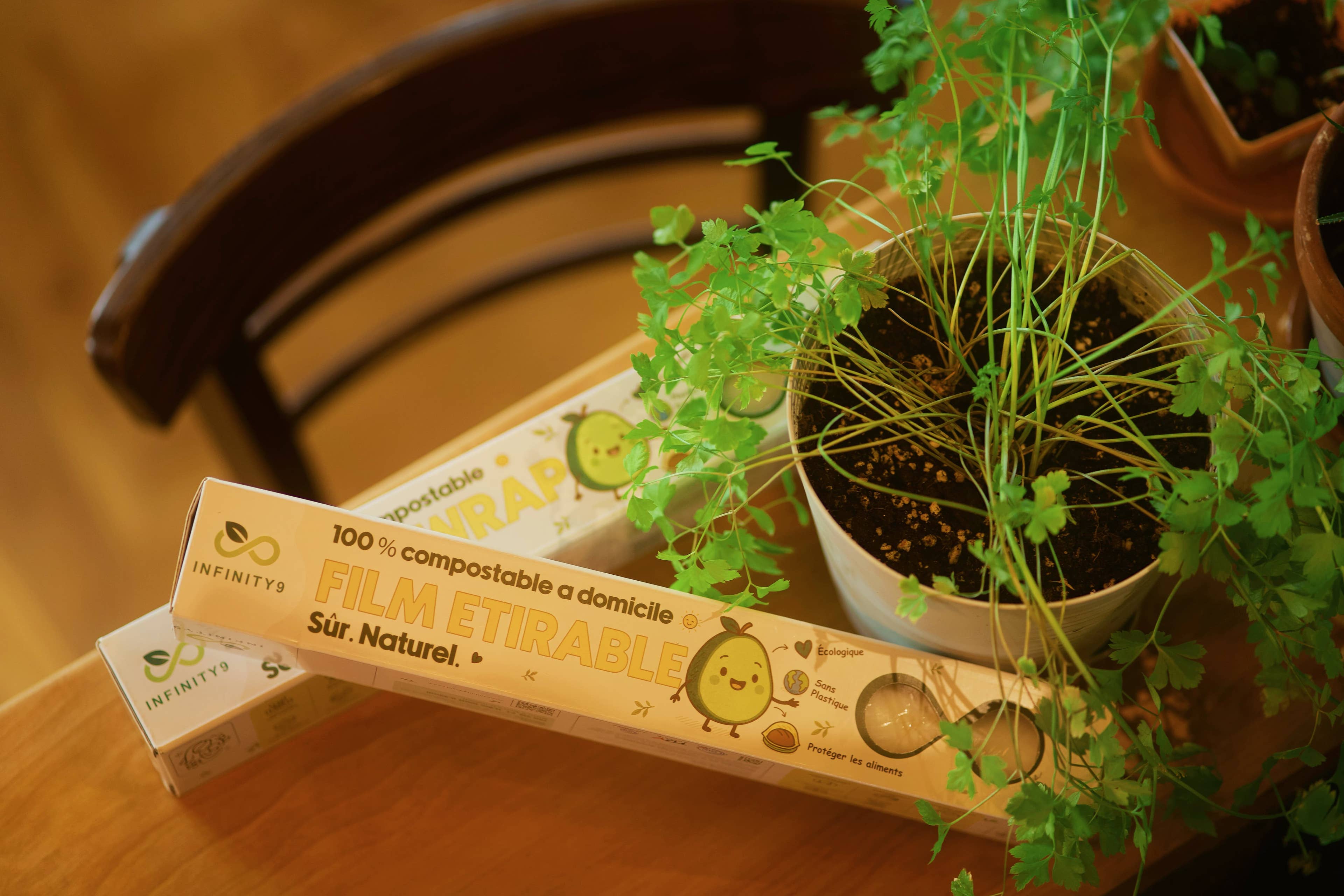 Compostable Infinity9 cling wrap packaging with a plant on a wooden surface